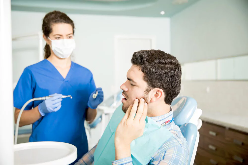 man suffering from toothache while looking at dentist